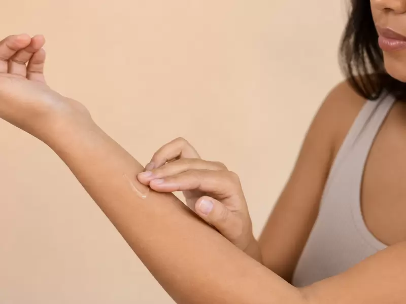 Adult carefully patch testing a skincare product on the inner arm
